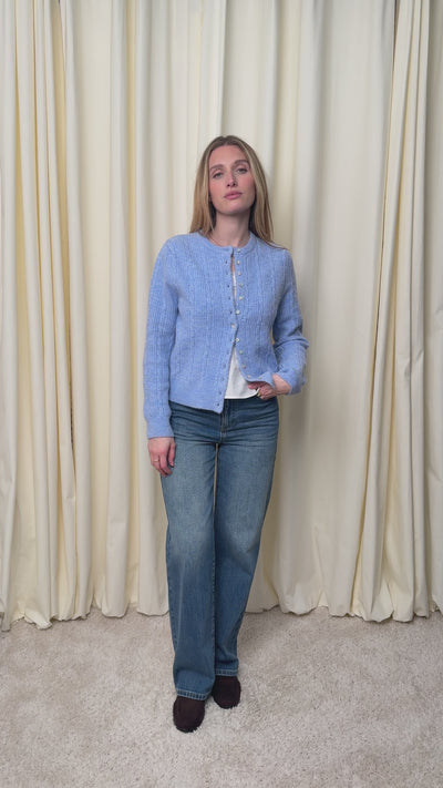 Cardigan bleu ciel en alpaga et laine mélangés à torsades fantaisie, encolure ronde et boutons en nacre. Une maille douce et chaleureuse au quotidien.